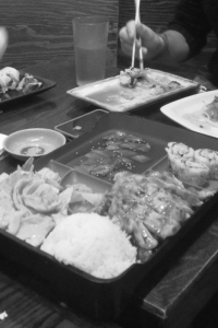 Appetizing teriyaki chicken bento box with tempura shrimp, white rice and California rolls. 