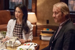 Joan Watson (Lucy Liu, left) has dinner with Mycroft Holmes (Rhys Ifans, right) as Sherlock Holmes leaves to work on the case.
