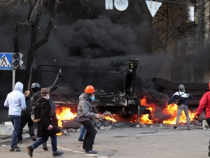 Protesters throwing bricks and Molotov cocktails at police behind the burning barricade.